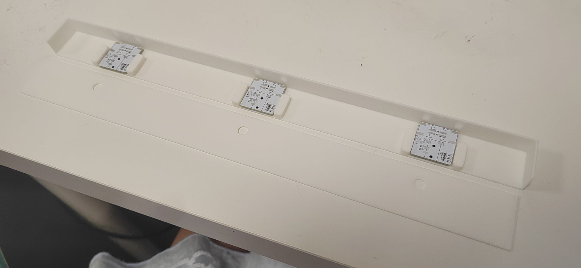 A 3D-printed case holding three small, square circuit board units.