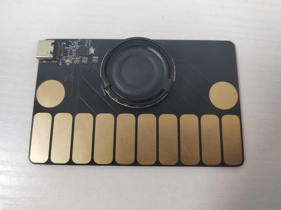 The entire assembled board, the speaker further bound by two thin stripes of black electrical tape.