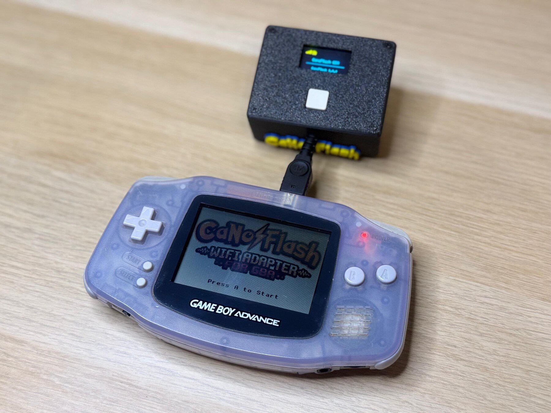 CanoFlash connected to an original Game Boy Advance, with its menu and OLED status display